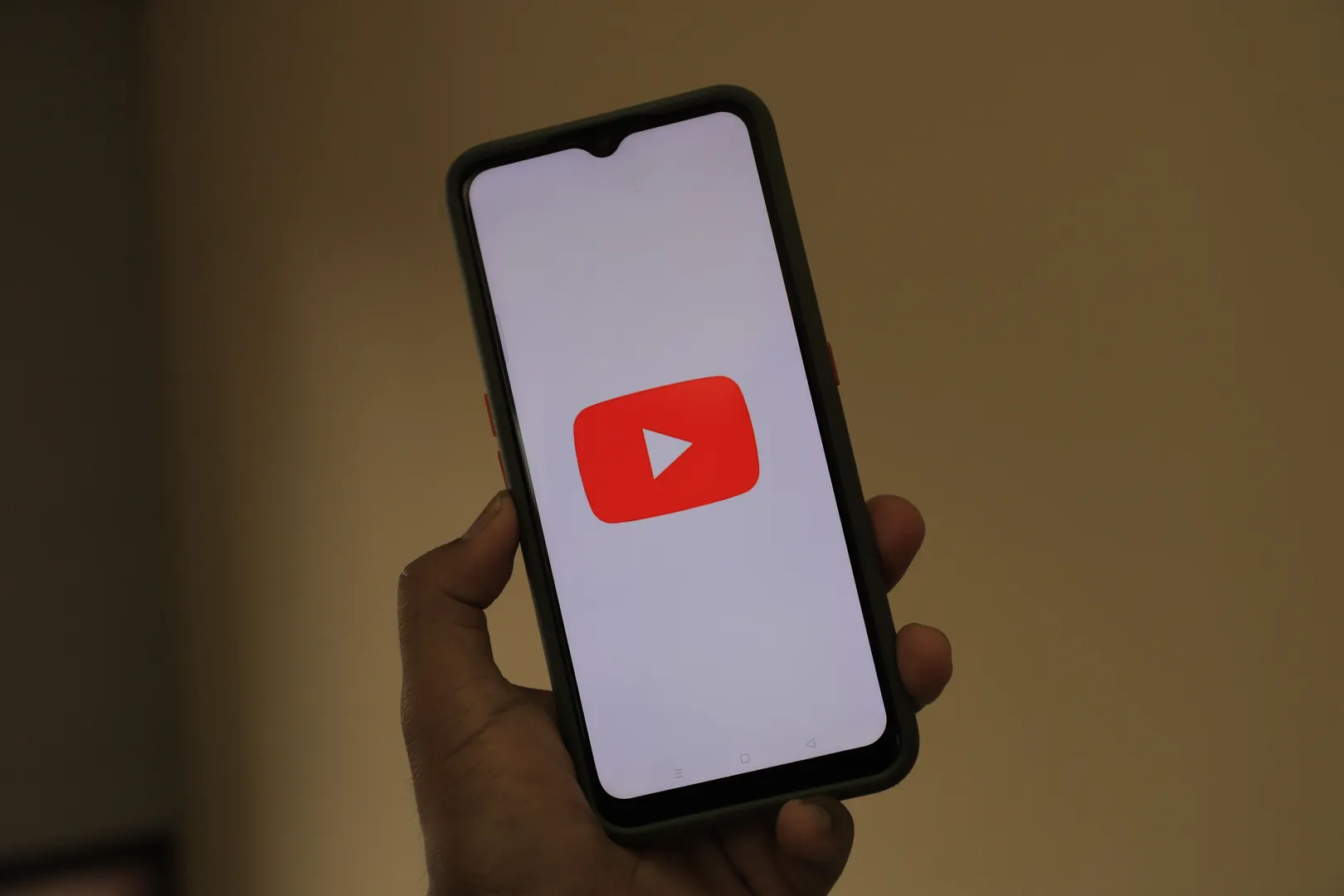 Someone holding a smartphone displaying the YouTube logo on the screen